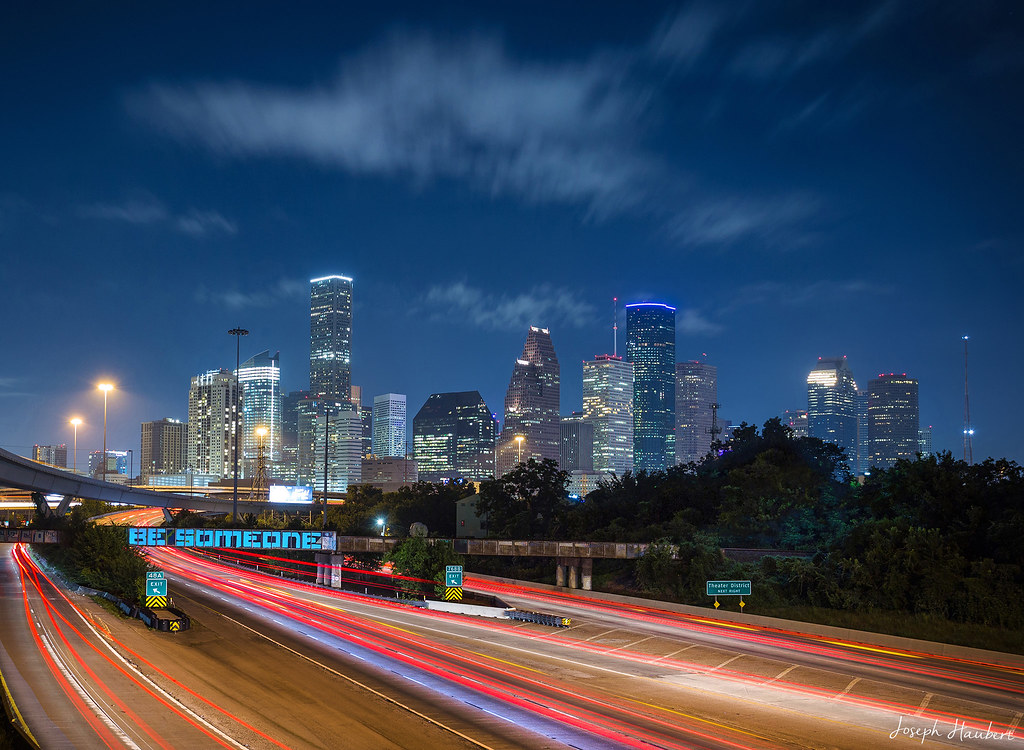 Downtown Houston skyline at dusk above the BE SOMEONE bridge